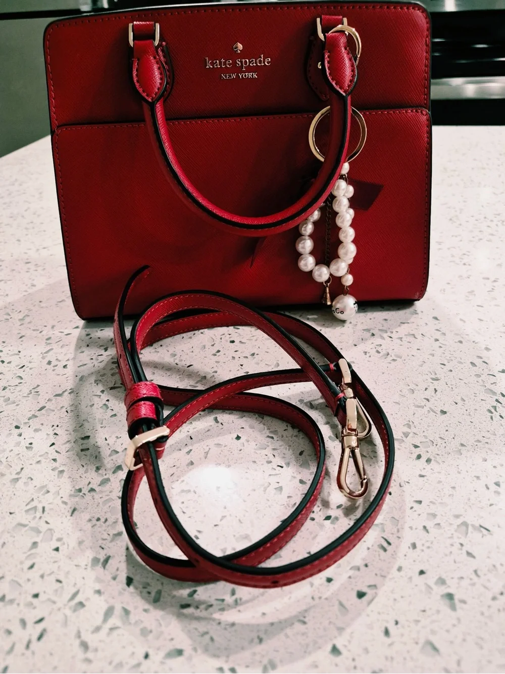 This red satchel is a Kate Spade New York Madison Saffiano Leather